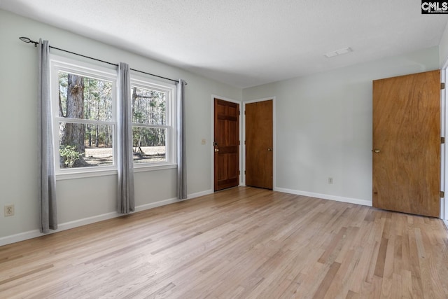 unfurnished bedroom with a textured ceiling and light wood-type flooring