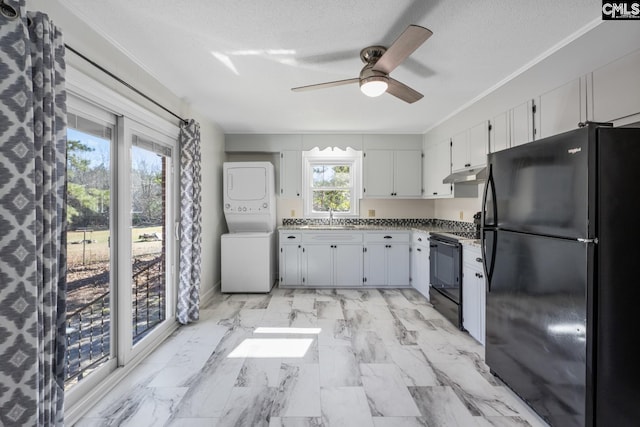 kitchen with a textured ceiling, sink, black appliances, white cabinets, and stacked washer / drying machine