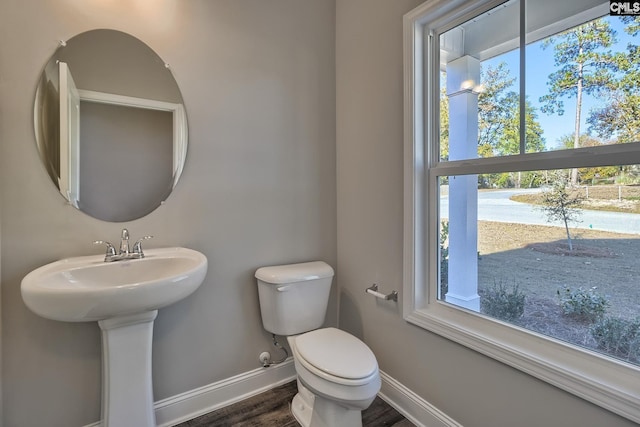 bathroom featuring toilet, wood finished floors, baseboards, and a sink