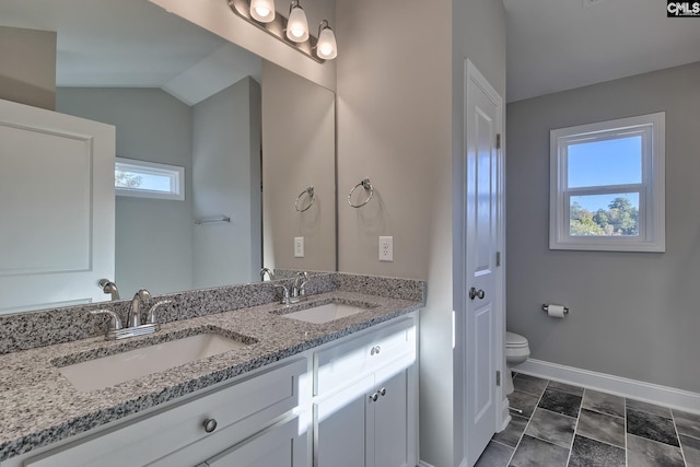 full bath featuring double vanity, toilet, baseboards, and a sink