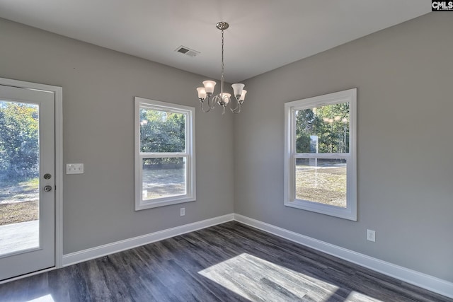 unfurnished dining area with visible vents, an inviting chandelier, dark wood-type flooring, and baseboards