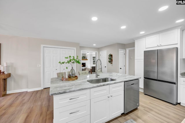 kitchen featuring white cabinets, sink, stainless steel appliances, and a center island with sink