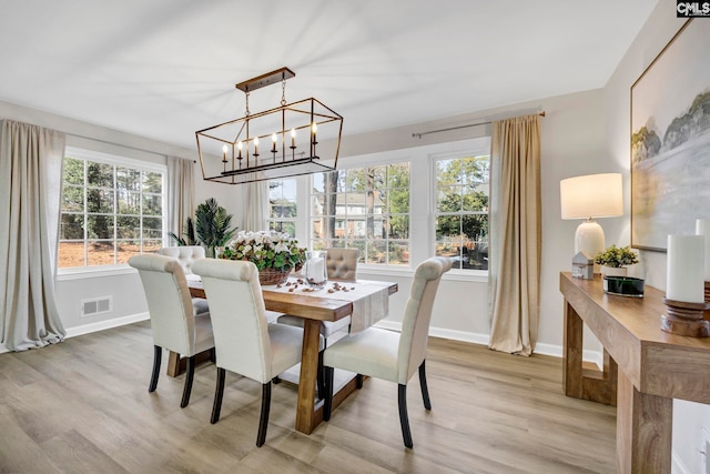 dining room featuring plenty of natural light, a notable chandelier, and light wood-type flooring