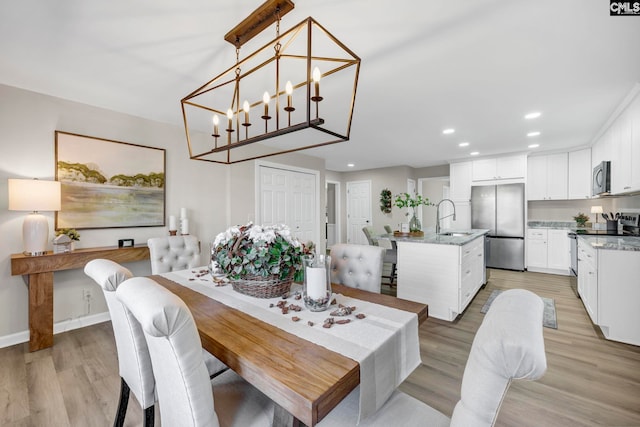 dining room with a chandelier, light wood-type flooring, and sink