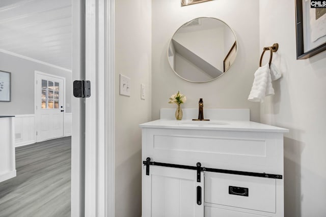 bathroom with crown molding, hardwood / wood-style floors, and vanity