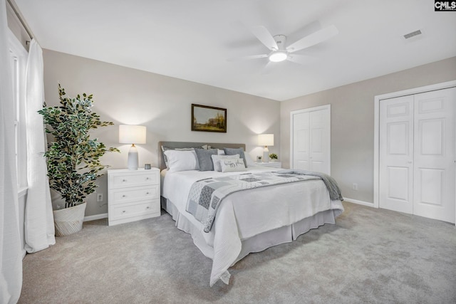 carpeted bedroom with ceiling fan and two closets