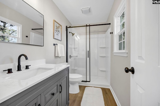 bathroom featuring toilet, vanity, an enclosed shower, and hardwood / wood-style flooring