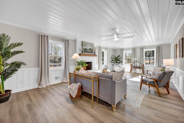 living room featuring a fireplace, light hardwood / wood-style flooring, and ceiling fan