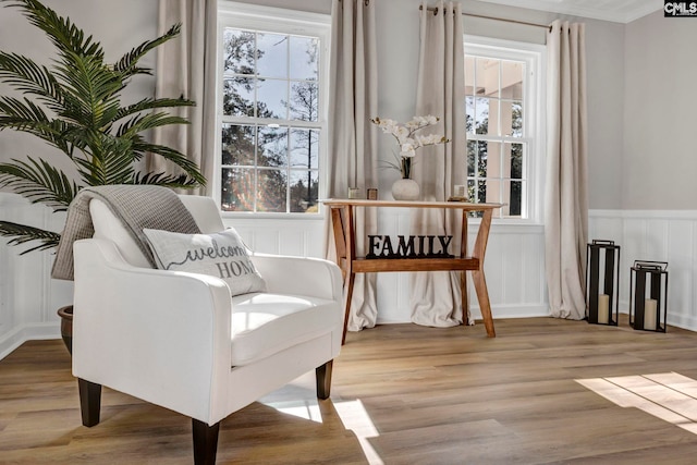 living area featuring crown molding, a wealth of natural light, and light hardwood / wood-style flooring