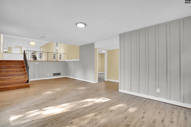 unfurnished living room with light hardwood / wood-style flooring and a chandelier