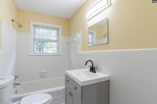 full bathroom featuring vanity, toilet, tiled shower / bath, and tile walls