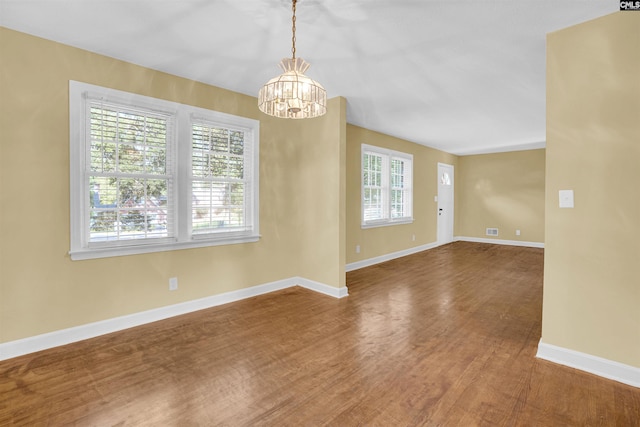 unfurnished room with a chandelier and hardwood / wood-style flooring