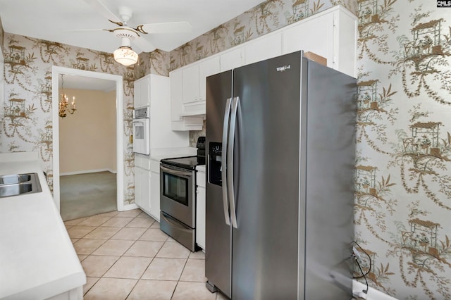 kitchen with ceiling fan with notable chandelier, sink, light tile patterned floors, white cabinetry, and stainless steel appliances