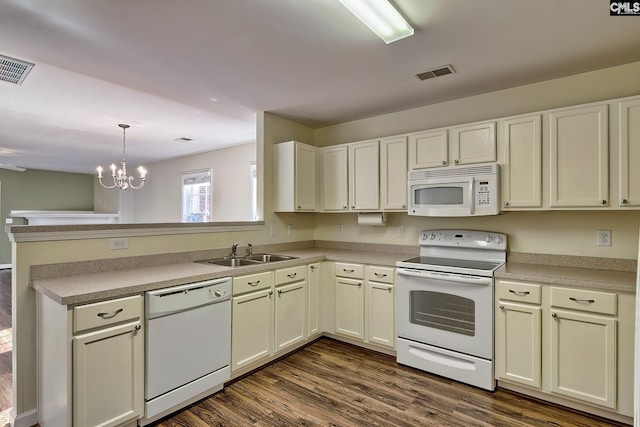 kitchen featuring kitchen peninsula, white appliances, sink, decorative light fixtures, and a chandelier