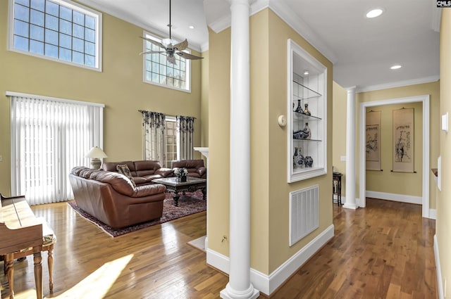 hallway with decorative columns, built in shelves, crown molding, and wood-type flooring