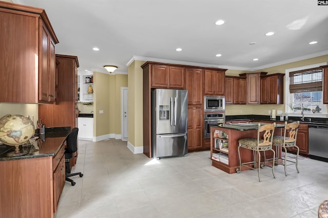 kitchen featuring stainless steel appliances, a kitchen breakfast bar, dark stone countertops, a kitchen island, and ornamental molding