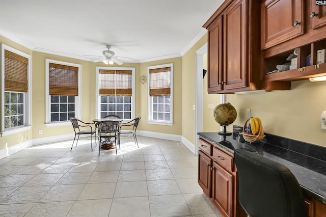 kitchen with plenty of natural light, ceiling fan, crown molding, and dark stone countertops