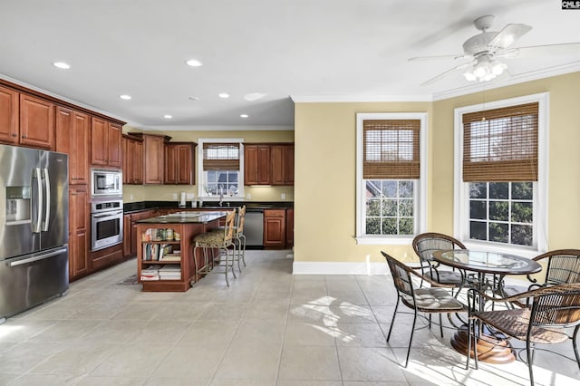 kitchen with appliances with stainless steel finishes, ornamental molding, a breakfast bar, sink, and a center island