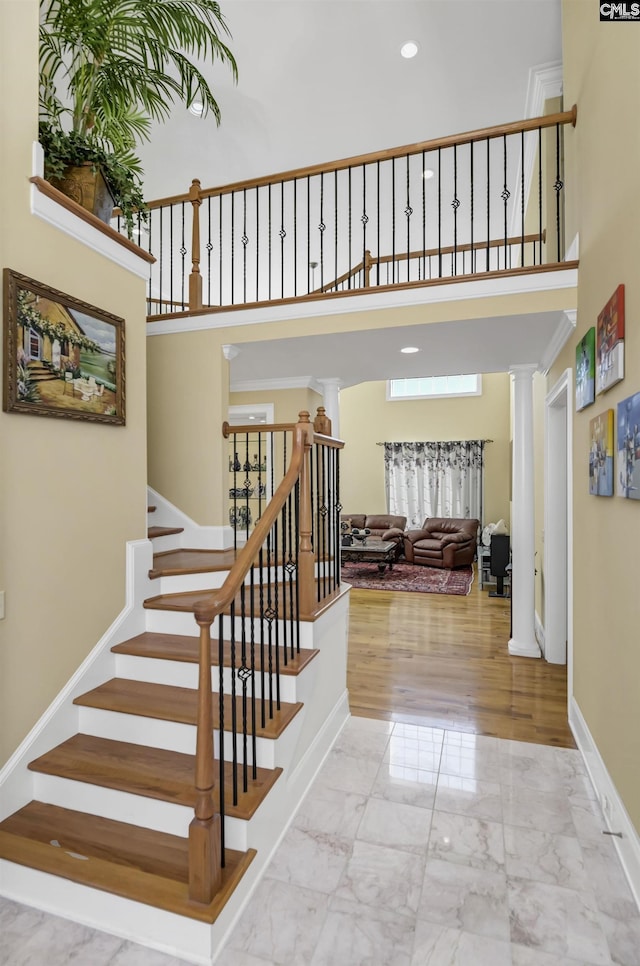 stairs featuring a high ceiling and decorative columns