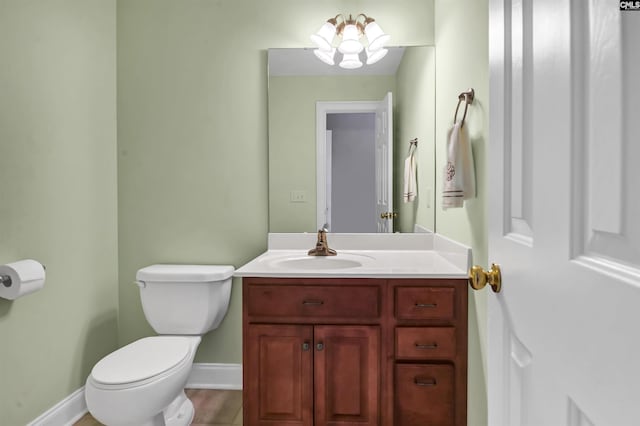 bathroom with a chandelier, vanity, and toilet