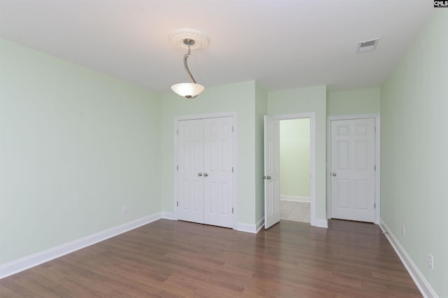 unfurnished bedroom with a closet and dark wood-type flooring