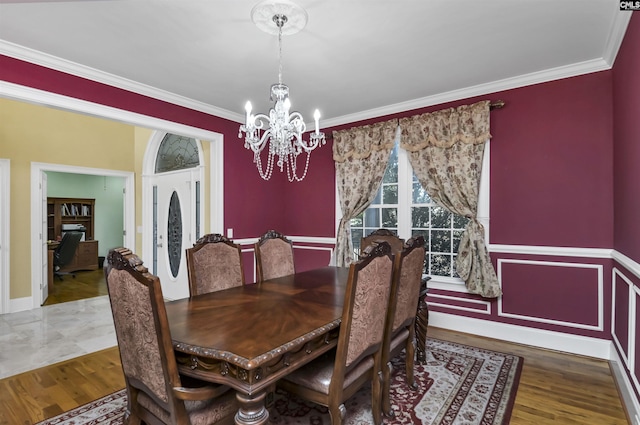 dining area with hardwood / wood-style floors, ornamental molding, and an inviting chandelier