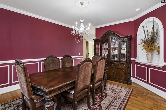 dining area featuring crown molding, wood-type flooring, and an inviting chandelier