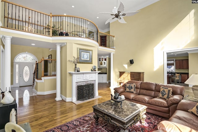 living room featuring decorative columns, ceiling fan, a high ceiling, and hardwood / wood-style flooring