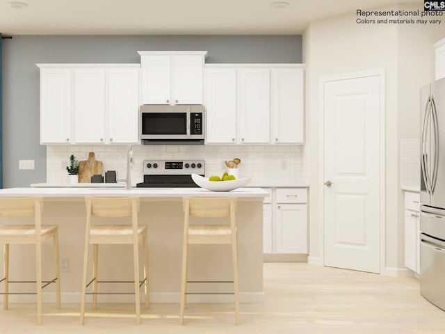 kitchen featuring a breakfast bar, decorative backsplash, white cabinetry, and appliances with stainless steel finishes