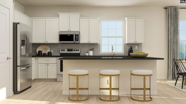 kitchen featuring a kitchen bar, white cabinetry, and stainless steel appliances