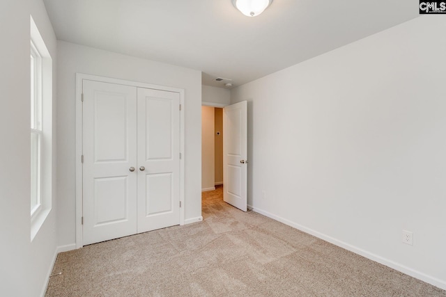 unfurnished bedroom featuring a closet and light colored carpet