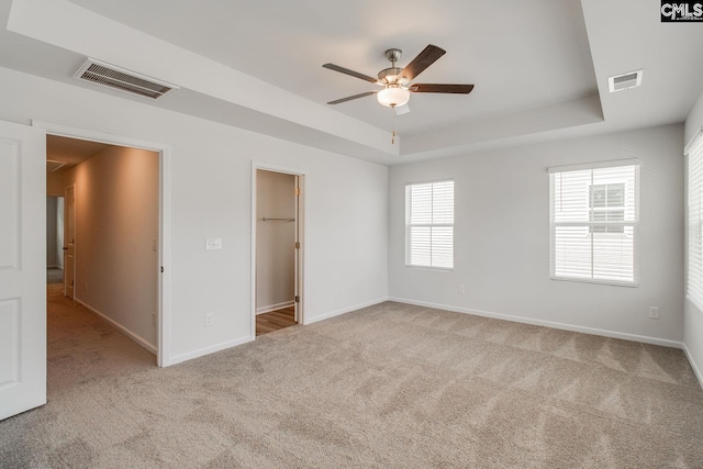 carpeted empty room with a tray ceiling and ceiling fan