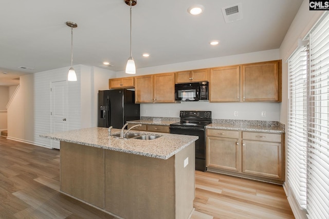 kitchen with hanging light fixtures, sink, an island with sink, and black appliances