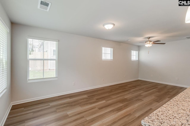 spare room featuring wood-type flooring, plenty of natural light, and ceiling fan