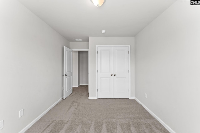 unfurnished bedroom with light colored carpet and a closet