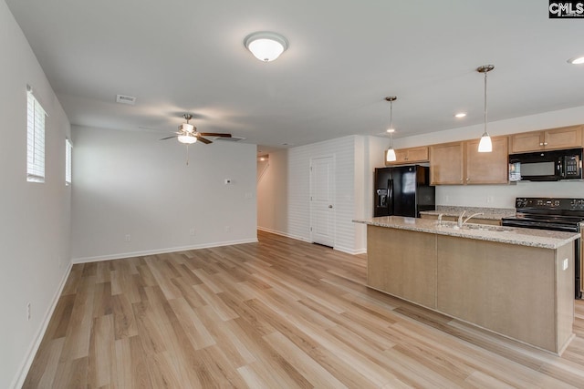 kitchen with light stone countertops, sink, light hardwood / wood-style flooring, decorative light fixtures, and black appliances