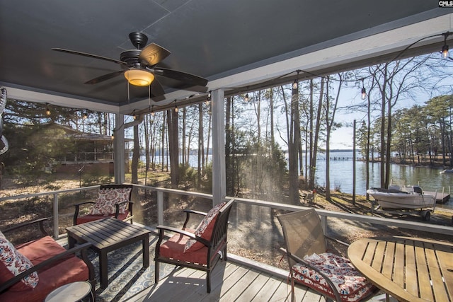 sunroom / solarium with ceiling fan and a water view