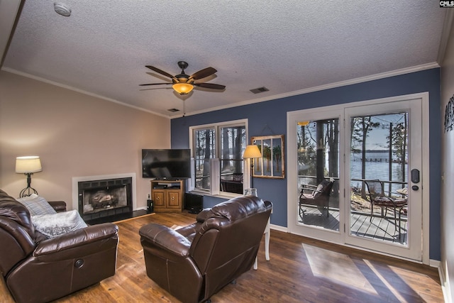 living room featuring a textured ceiling, ceiling fan, wood-type flooring, and a fireplace