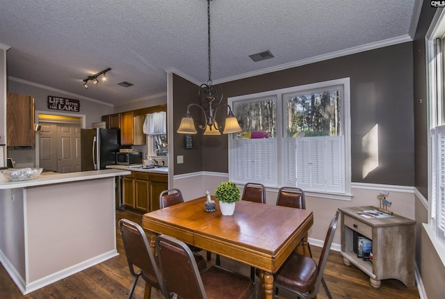 dining area featuring dark hardwood / wood-style flooring, a textured ceiling, ornamental molding, and a notable chandelier