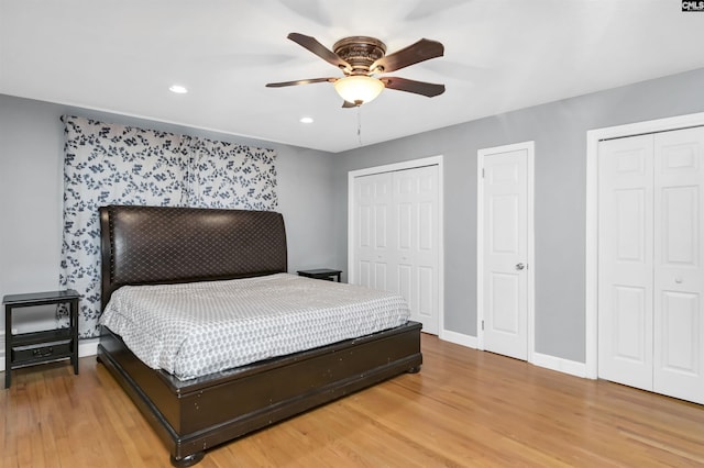 bedroom with ceiling fan, wood-type flooring, and two closets