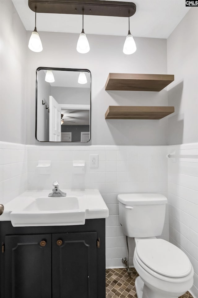 bathroom with tile patterned flooring, vanity, toilet, and tile walls