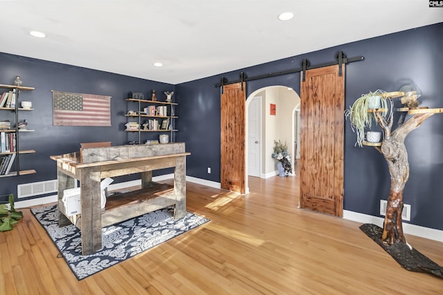 home office featuring hardwood / wood-style floors and a barn door