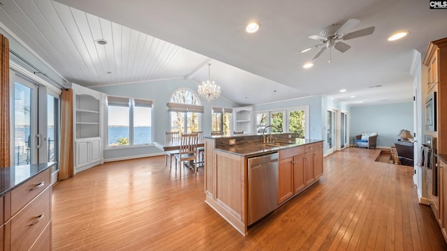 kitchen featuring a center island with sink, a water view, sink, decorative light fixtures, and stainless steel appliances