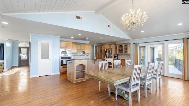 dining area featuring a chandelier, vaulted ceiling with beams, and light hardwood / wood-style flooring