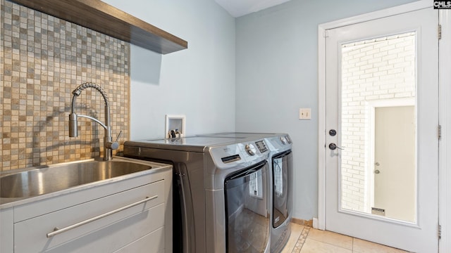 laundry room with light tile patterned flooring, washing machine and dryer, and sink