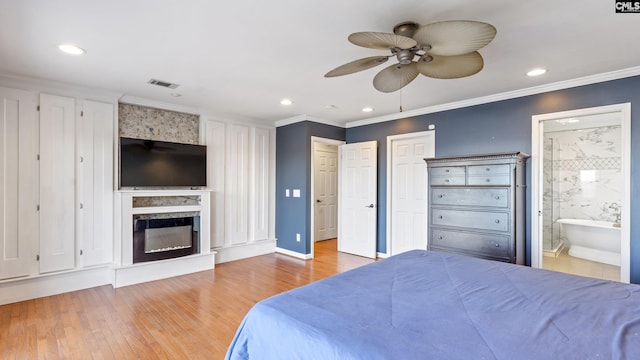 bedroom featuring ceiling fan, crown molding, light wood-type flooring, and ensuite bathroom