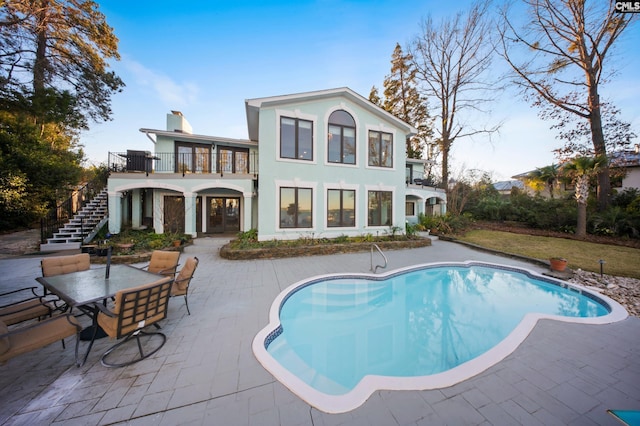 rear view of property featuring a balcony and a patio