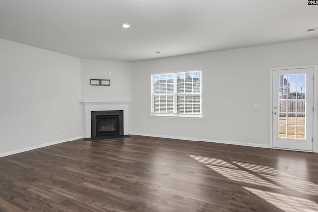 unfurnished living room featuring dark hardwood / wood-style flooring and plenty of natural light