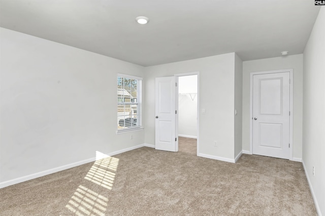 unfurnished bedroom with light colored carpet, a walk in closet, and a closet