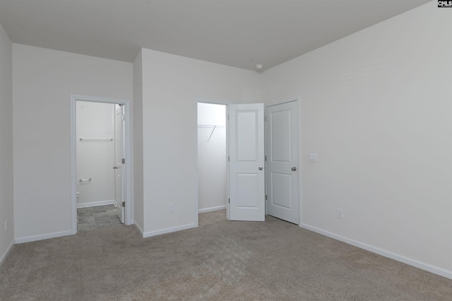 unfurnished bedroom with light colored carpet, a spacious closet, and a closet